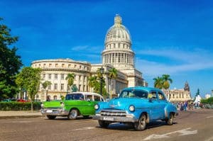 HAVANA, CUBA - DECEMBER 2, 2013: Old classic American cars rides in front of the Capitol. Before a new law issued on October 2011, cubans could only trade cars that were on the road before 1959.